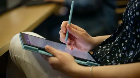 Hands taking notes on tablet.