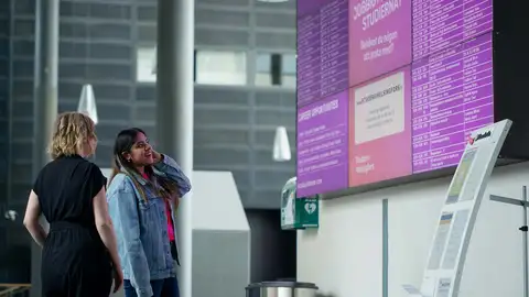 Two people looking at Arcada's information board.