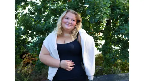 Studentambassadör står ute vid träden